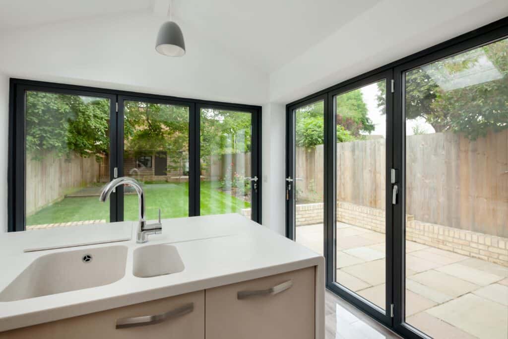 Two black framed bifold doors placed within a modern white kitchen